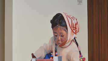 Un gran mural que muestra a un niño jugando con un pájaro y una casa.