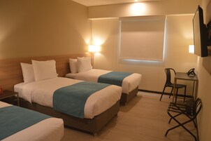 A hotel room with two beds, a desk, and a chair.