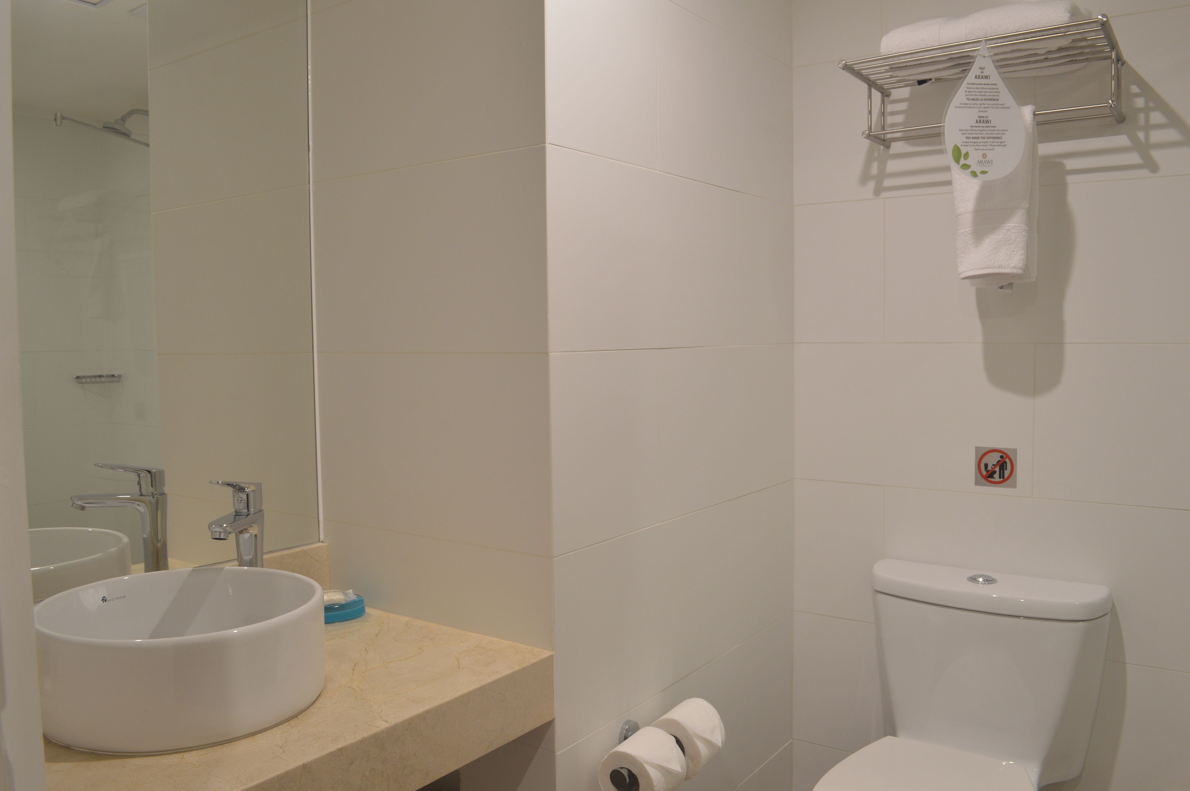 Un baño con un lavamanos redondo, un inodoro y un perchero para toallas.
