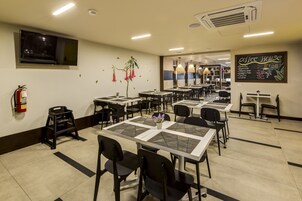 Un restaurante limpio y bien iluminado con varias mesas y sillas, un extintor y un menú en una pizarra en la pared.