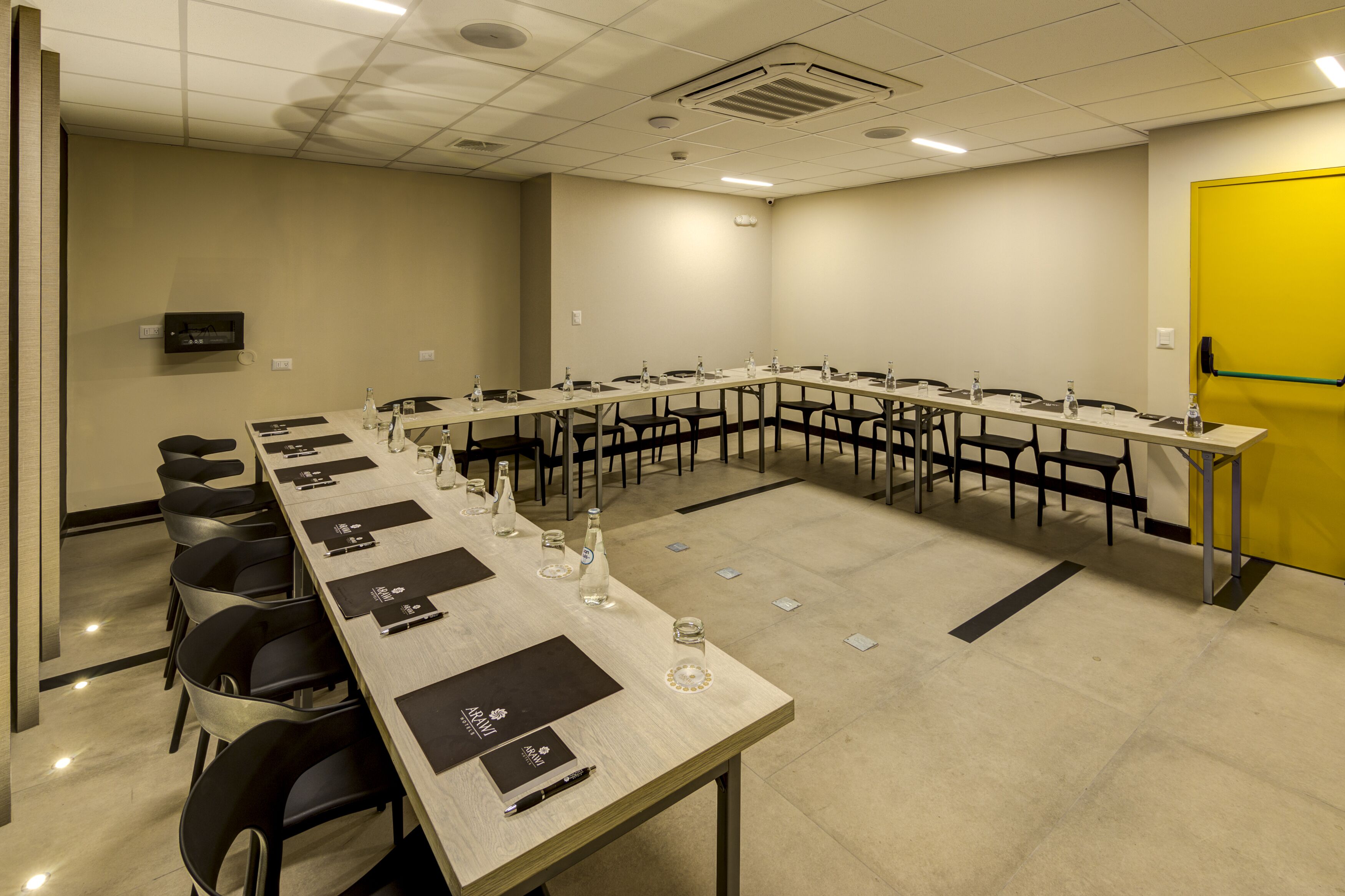 A conference room with a long table, chairs, water bottles, and nameplates.