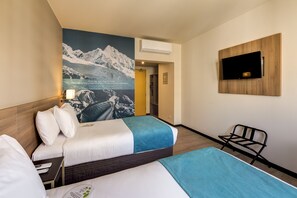 A hotel room with two beds, a mounted TV, and a mountain landscape poster. - Arawi Miraflores Express (Lima)