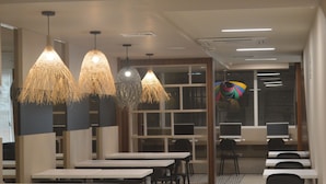 A modern library or study area with multiple tables and chairs, large windows, and hanging lamps. - Arawi Miraflores Express (Lima)
