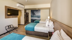 A hotel room with two beds, a TV mounted on the wall, a wooden headboard, a wall-mounted air conditioner, and a poster of a beach scene. - Arawi Miraflores Express (Lima)