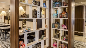 A room with a patterned floor, wooden shelving with various decorative items, and a dining area with chairs and a table. - Arawi Miraflores Express (Lima)