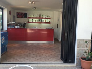 Cozinha com ilha vermelha, máquina de café e diversos frascos nas prateleiras.