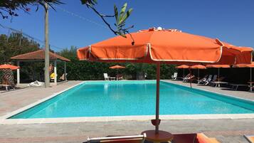 Une piscine avec des chaises longues et des parasols orange.