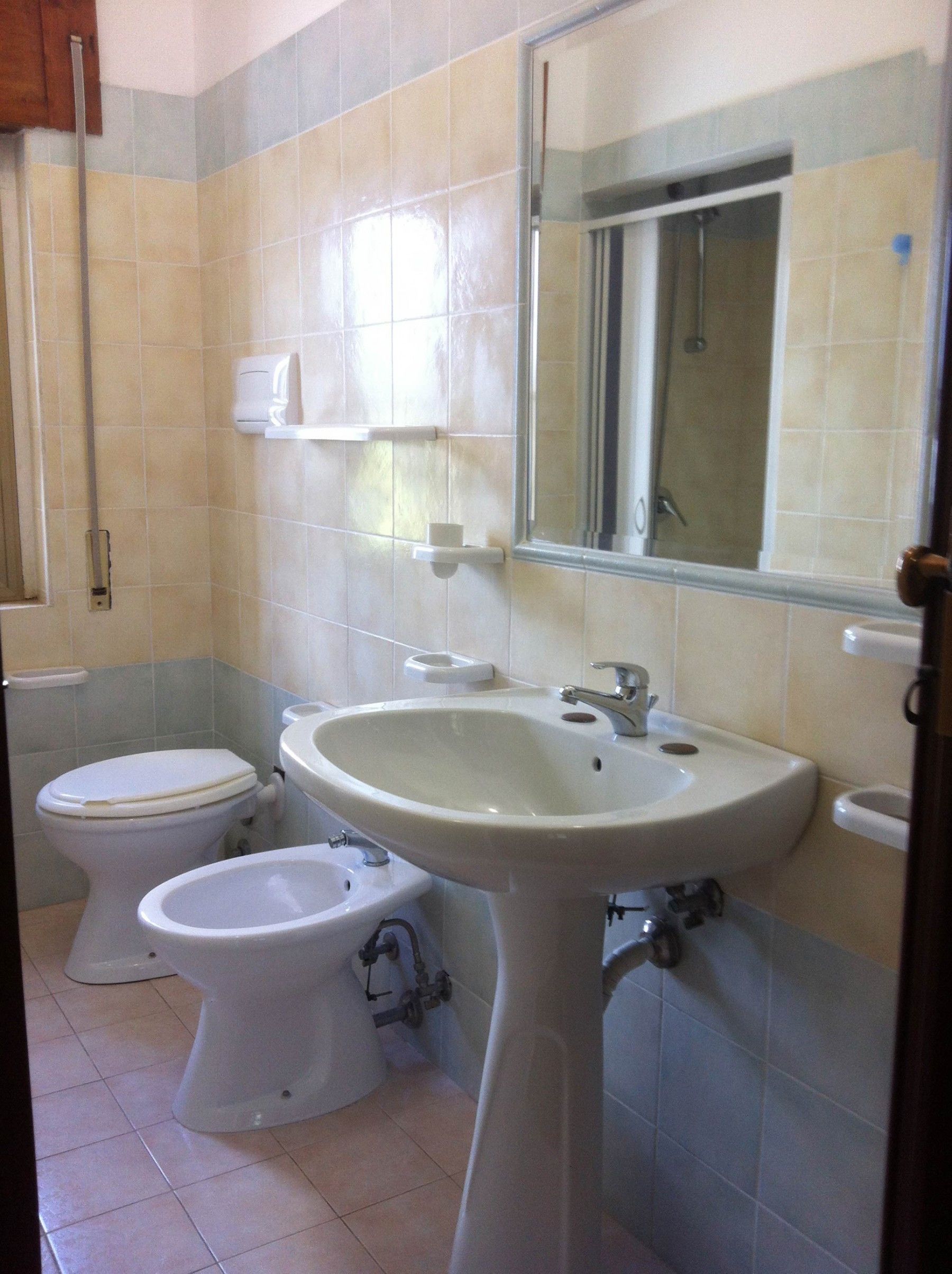 Et badeværelse med toilet, bidet og håndvask.