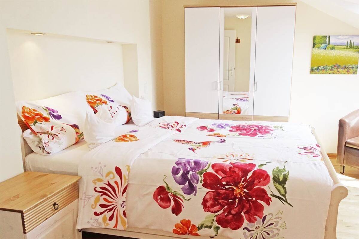 Une chambre à coucher avec un lit, une chaise, une armoire et un tableau accroché au mur.
