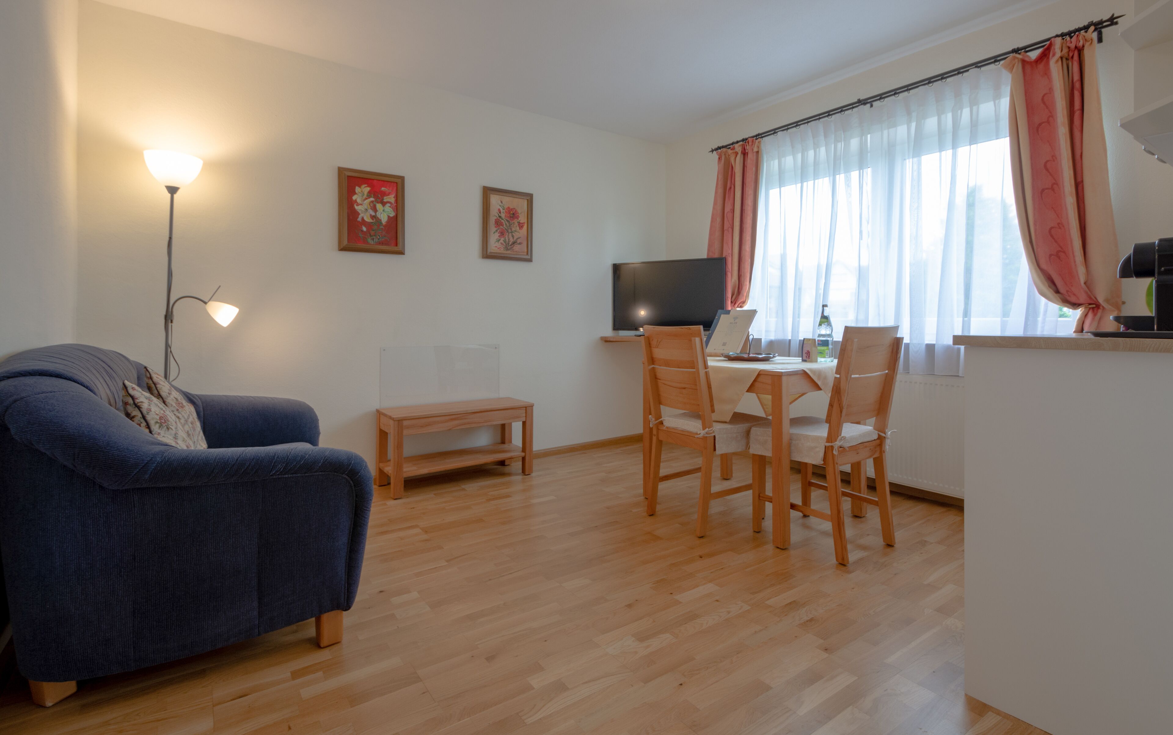 Una sala de estar con sofá, mesa de centro, televisor y un comedor con sillas y mesa.