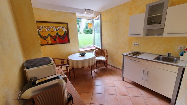 Una cocina compacta con comedor, una ventana con vistas y un cuadro en la pared.