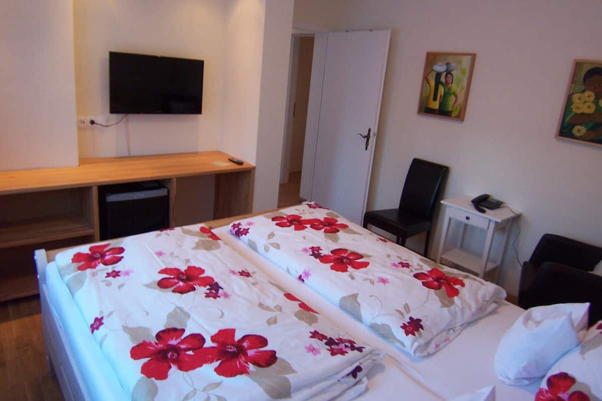 Une chambre d’hôtel avec deux lits, un bureau, une chaise, une télévision et une porte.
