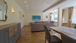 Ein modernes Hotelzimmer mit einem Holzespeisetisch, einer Couch, einem großen Spiegel und einem Fernseher.