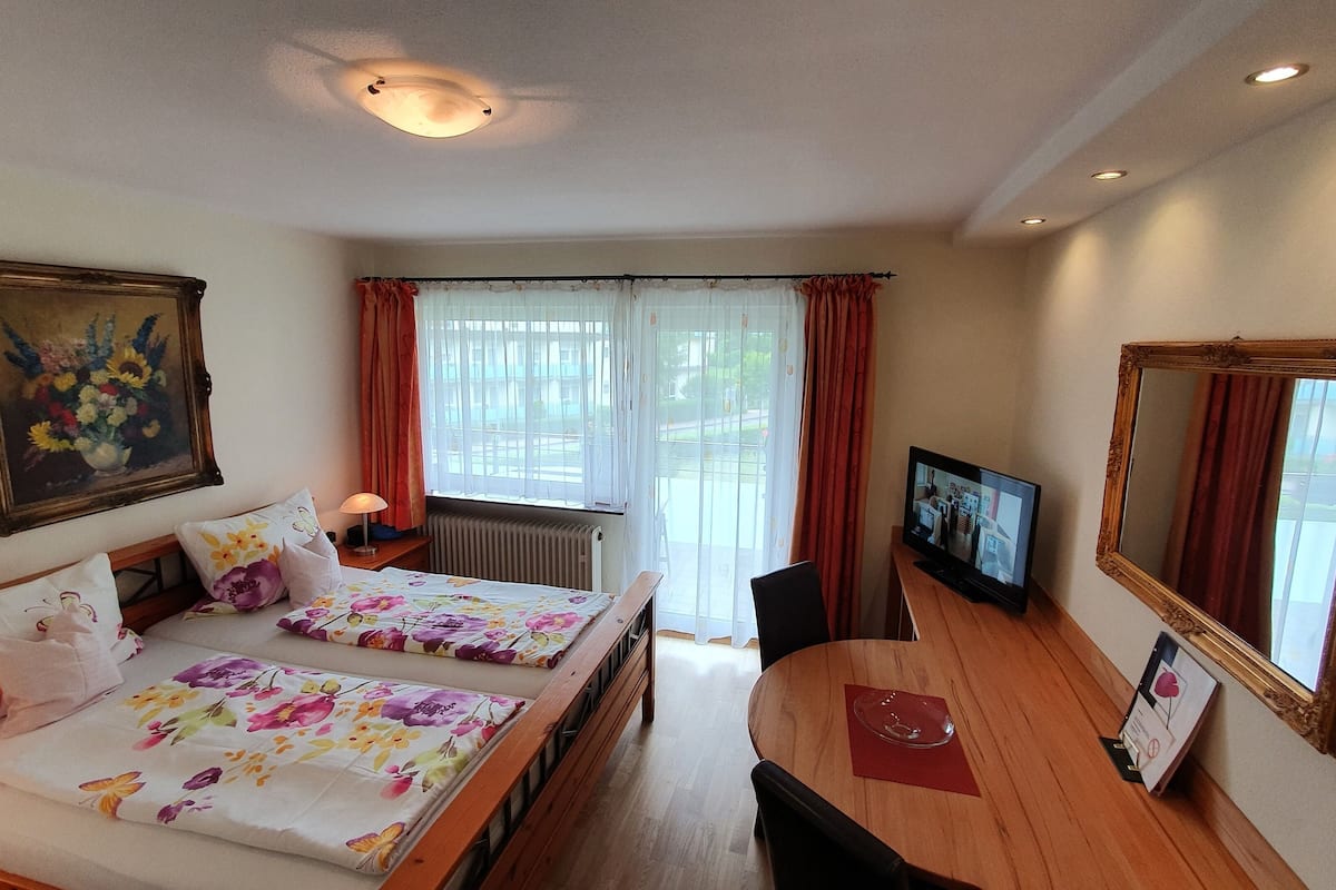 Une chambre d’hôtel avec deux lits, une table à manger, un téléviseur, un miroir et un tableau au mur.