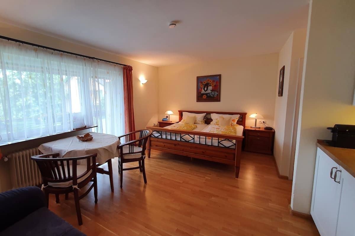 Une pièce confortable avec un lit en bois, une table à manger avec des chaises, un téléviseur et un radiateur.