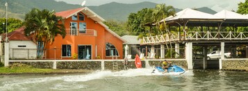 Un jet acuático en un río, con una casa y un área cubierta al fondo.