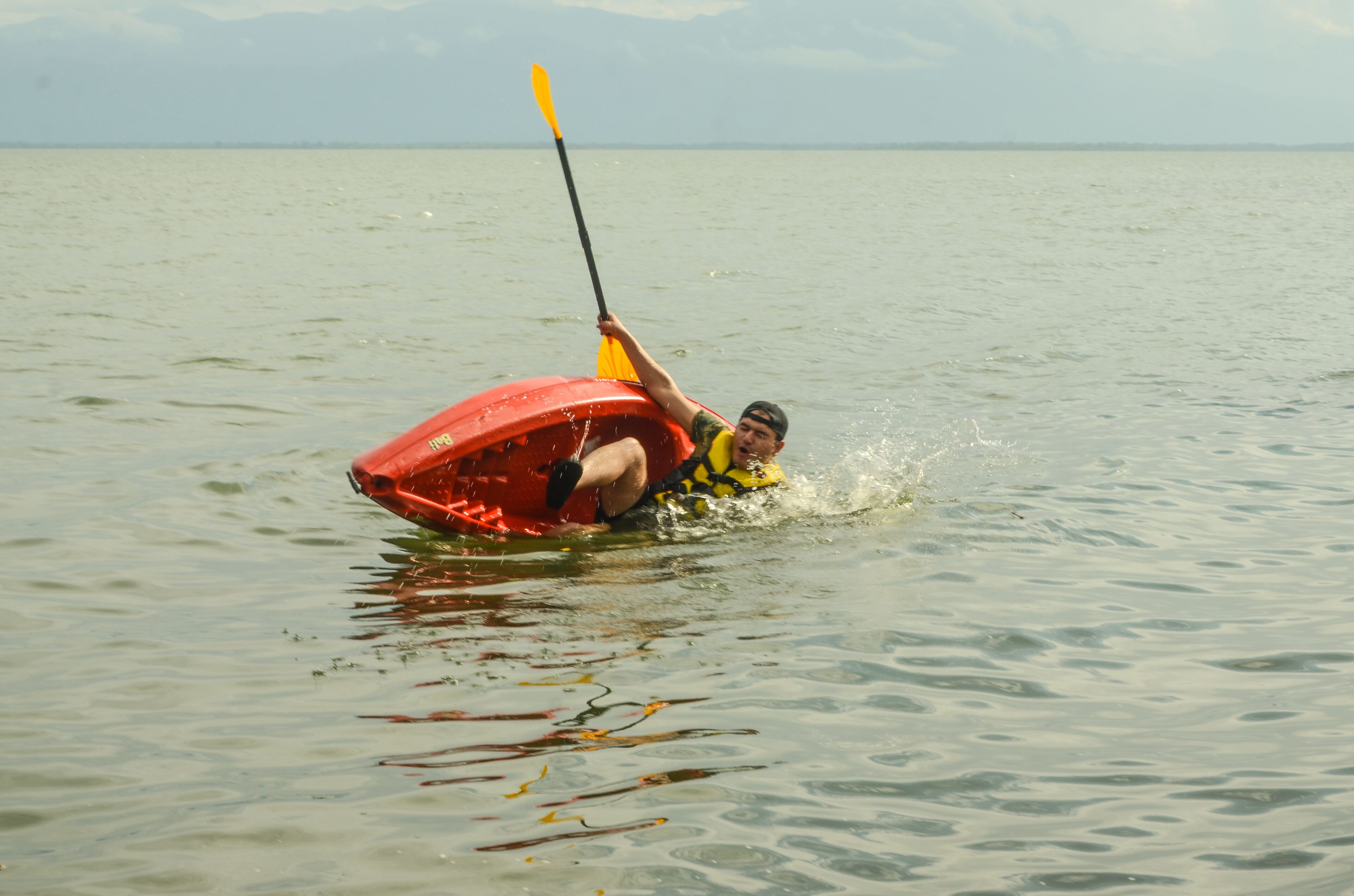 Una persona en un kayak rojo sobre un agua tranquila.