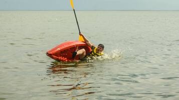 Una persona en un kayak rojo sobre un agua tranquila.