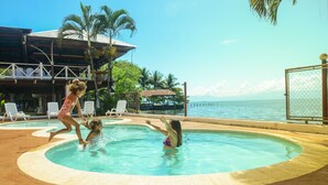 A swimming pool with a view of the ocean, surrounded by lounge chairs and palm trees. - Chalet Castillo (El Estor)