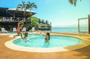 Una piscina con vista al océano, rodeada de tumbonas y palmeras.