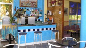 A bar area with stools, a counter with bottles, and a painting on the wall. - Hotel Bellevue (Cesenatico)
