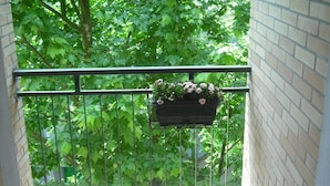 A balcony with a metal railing, a hanging planter with flowers, and a brick wall. - Hotel Bellevue (Cesenatico)