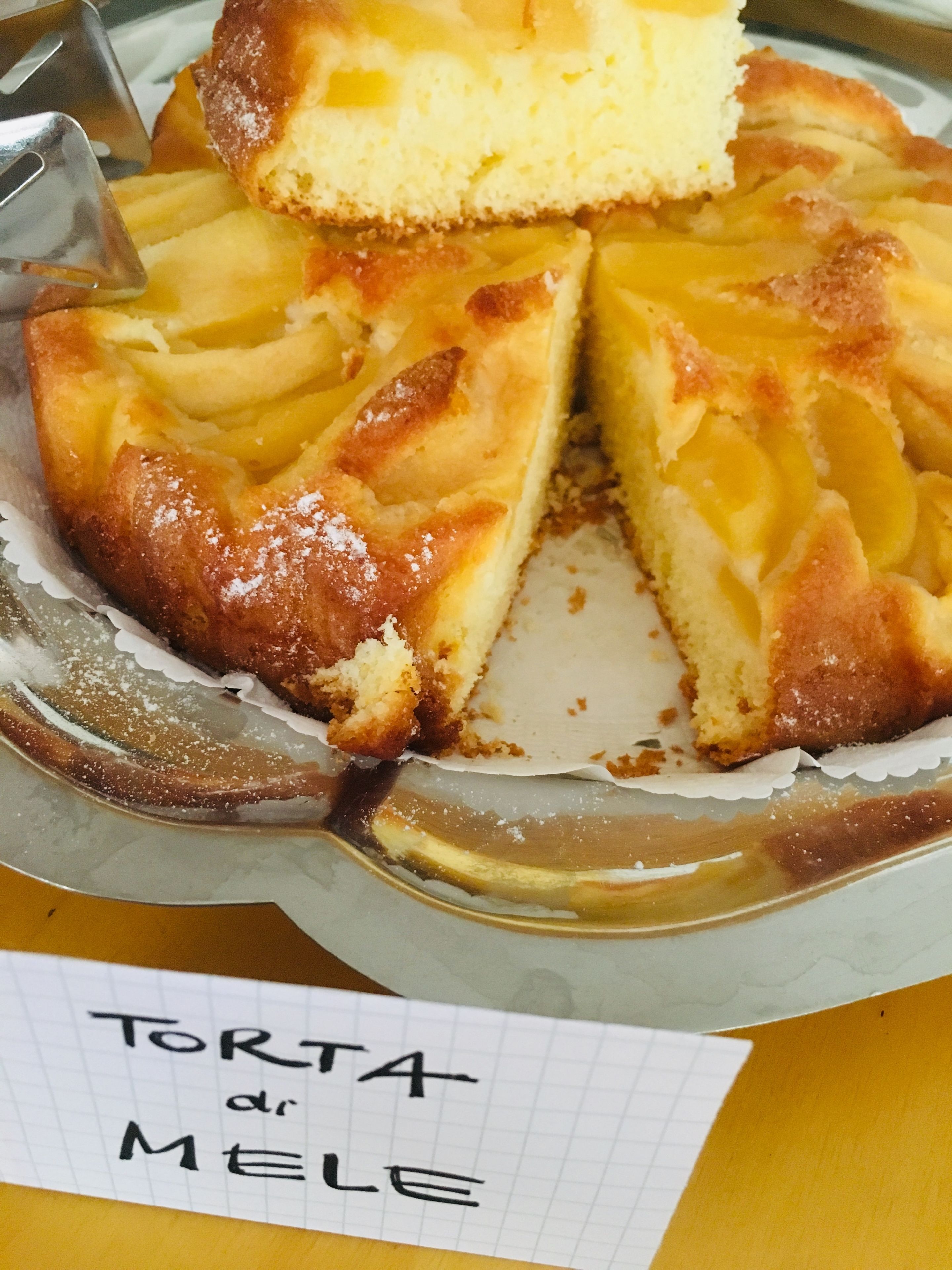 A slice of apple cake with a label reading "Torta di mele".