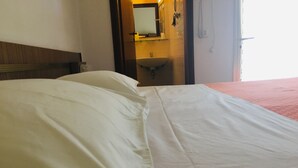 A hotel room with a bed, a bathroom visible through an open door, and a partial view of a window. - Hotel Bellevue (Cesenatico)