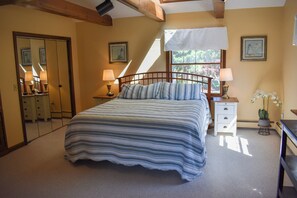Ein Schlafzimmer mit Bett, Nachttischen, einem Fenster und einem Spiegel.
