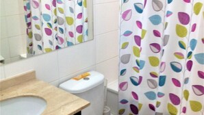 Een badkamer met toilet, wastafel en douchegordijn.