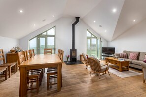 A spacious loft with a dining area, a fireplace, a television, and a sofa.