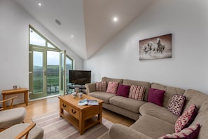 A spacious living room with a large sofa, a coffee table, and a television.