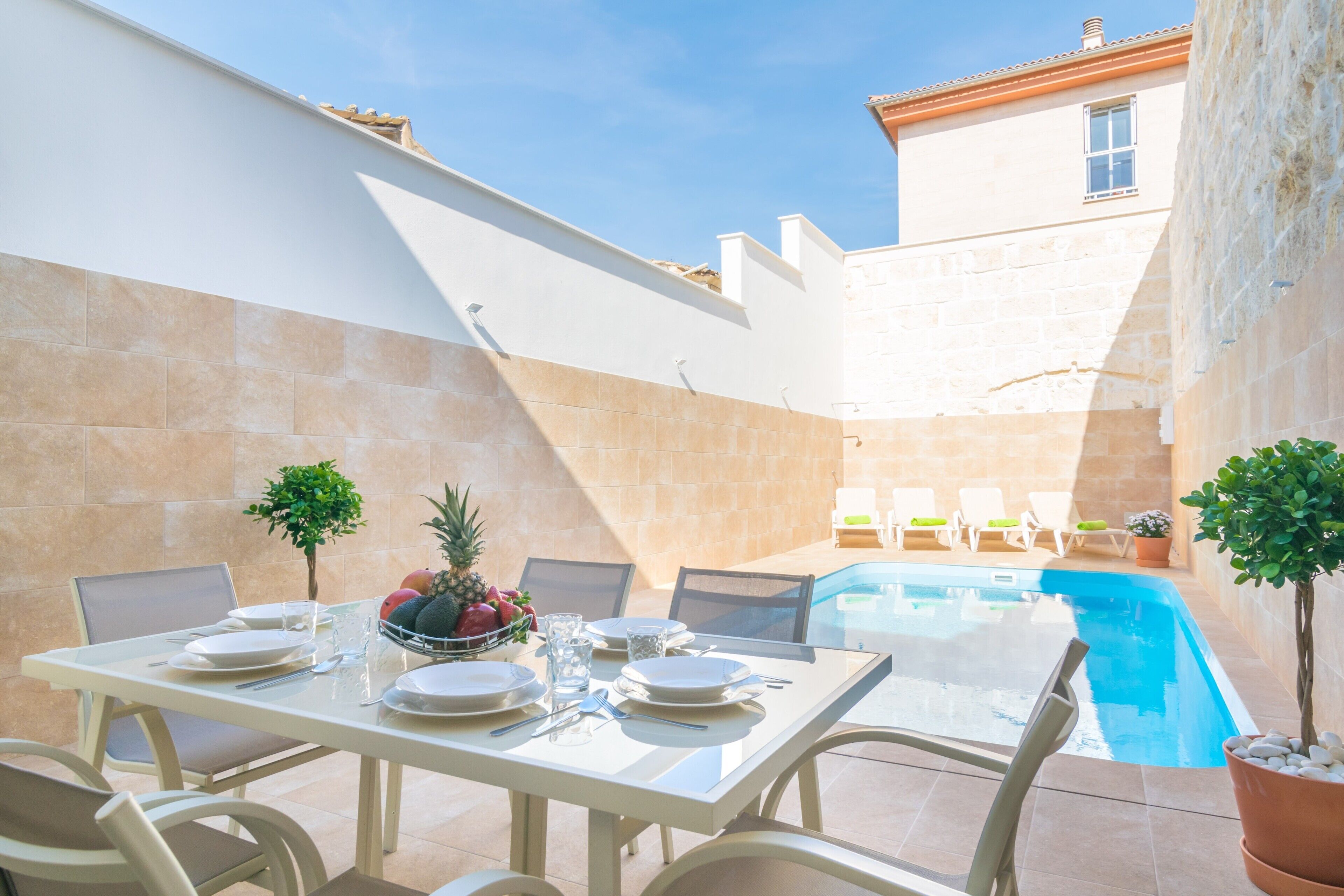 Comedor con piscina, sillas de exterior y una mesa dispuesta para cuatro.
