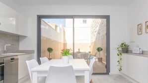 A modern kitchen with a dining area, a dishwasher, and a view of the courtyard.