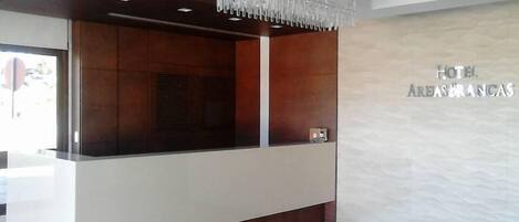 Un mostrador de recepción de hotel con diseño moderno, una araña de cristal y un letrero en la pared.