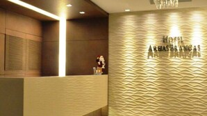 Un área de recepción con diseño moderno, que incluye un mostrador de recepción, una pared con textura y un cartel que dice 