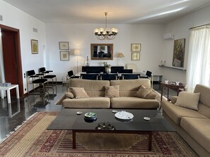 Un salon avec un canapé beige, une table basse et un coin repas comprenant des chaises et une table.