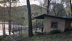 A small stone building with a porch, surrounded by trees and a body of water. - NORRIS LAKE FRONT RENTALS : CAMP RUN A MUK-LAKE FRONT with PRIVATE DOCK (Lafollette)