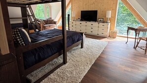 A loft bedroom with a bunk bed, a TV, a dresser, and a large window. - NORRIS LAKE FRONT RENTALS : CAMP RUN A MUK-LAKE FRONT with PRIVATE DOCK (Lafollette)