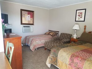 Un dormitorio con cama, una silla, un escritorio y un cuadro en la pared.