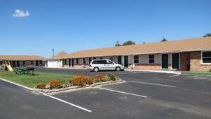 Un motel doté d’un parking, d’une table de pique-nique et d’une voiture garée devant.