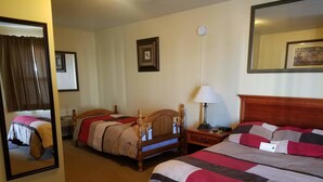 Une chambre d’hôtel avec deux lits simples, une table de chevet avec une lampe, une horloge et un miroir.