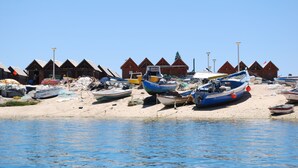 A beach with boats and wooden huts. - Quinta dos Cochichos – Country Houses (Olhao)