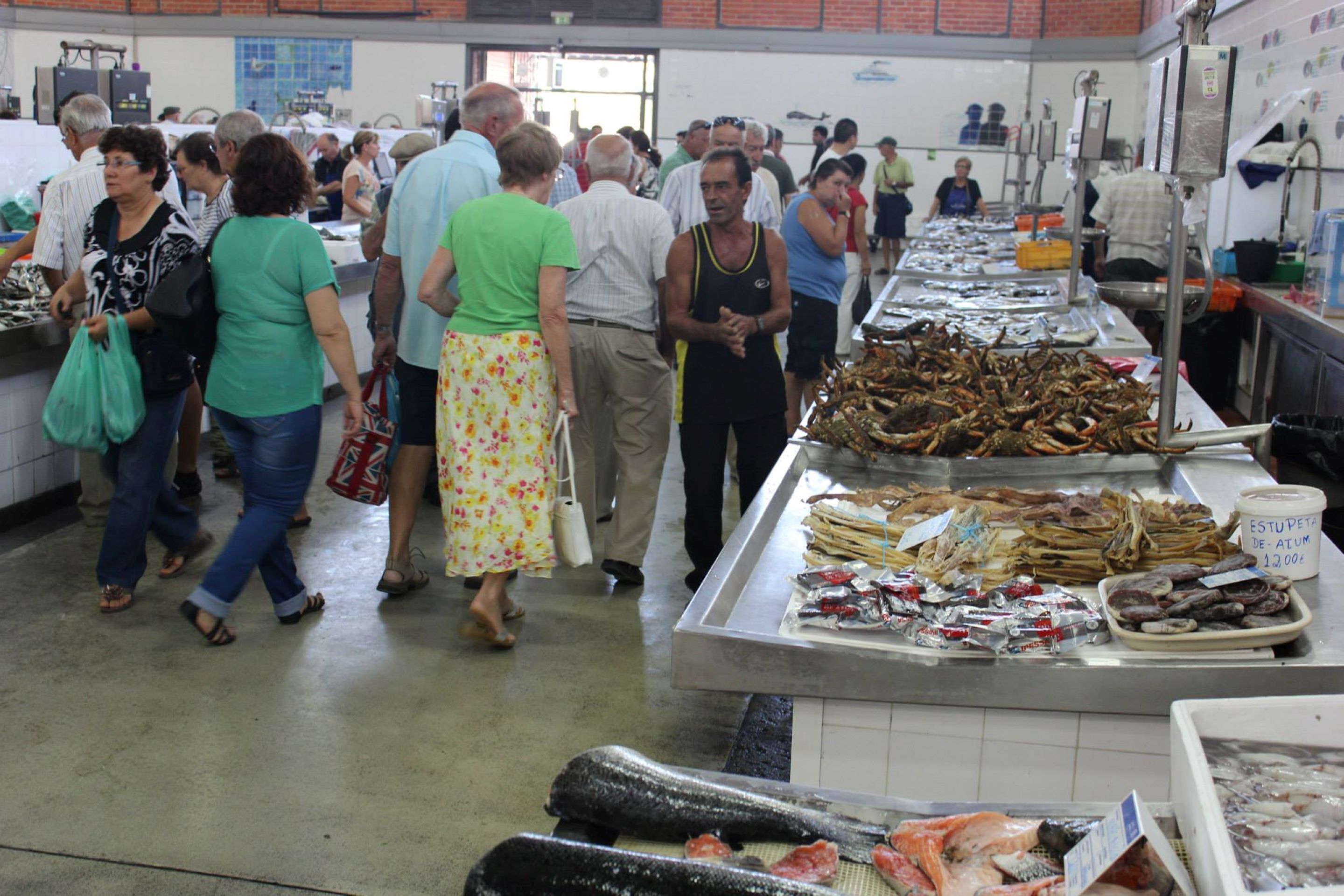 A busy market with people browsing seafood displays.
