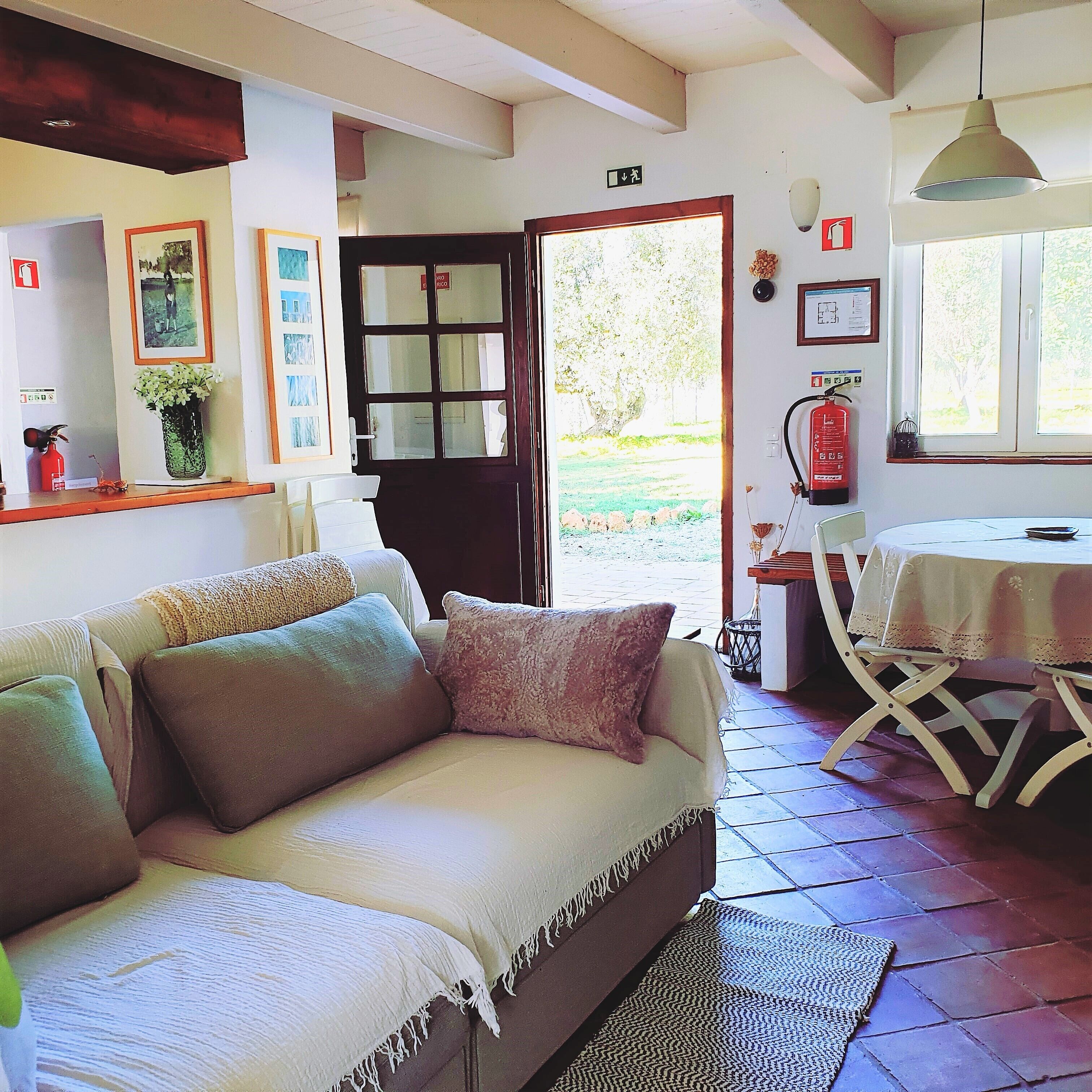 A cozy living room with a sofa, a dining table, and a fire extinguisher.