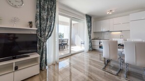 A modern kitchen with white cabinets, a built-in oven, and a dining area with white chairs. - Apartments with Outdoor Heated Pool, Terrace and free WIFI (Novalja)