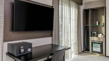 A modern hotel room with a flat-screen TV mounted on the wall, a small refrigerator, and a microwave on the counter.