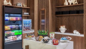 Un bar servant des collations, équipé d’un distributeur automatique, agrémenté d’une plante en pot et proposant divers produits alimentaires.
