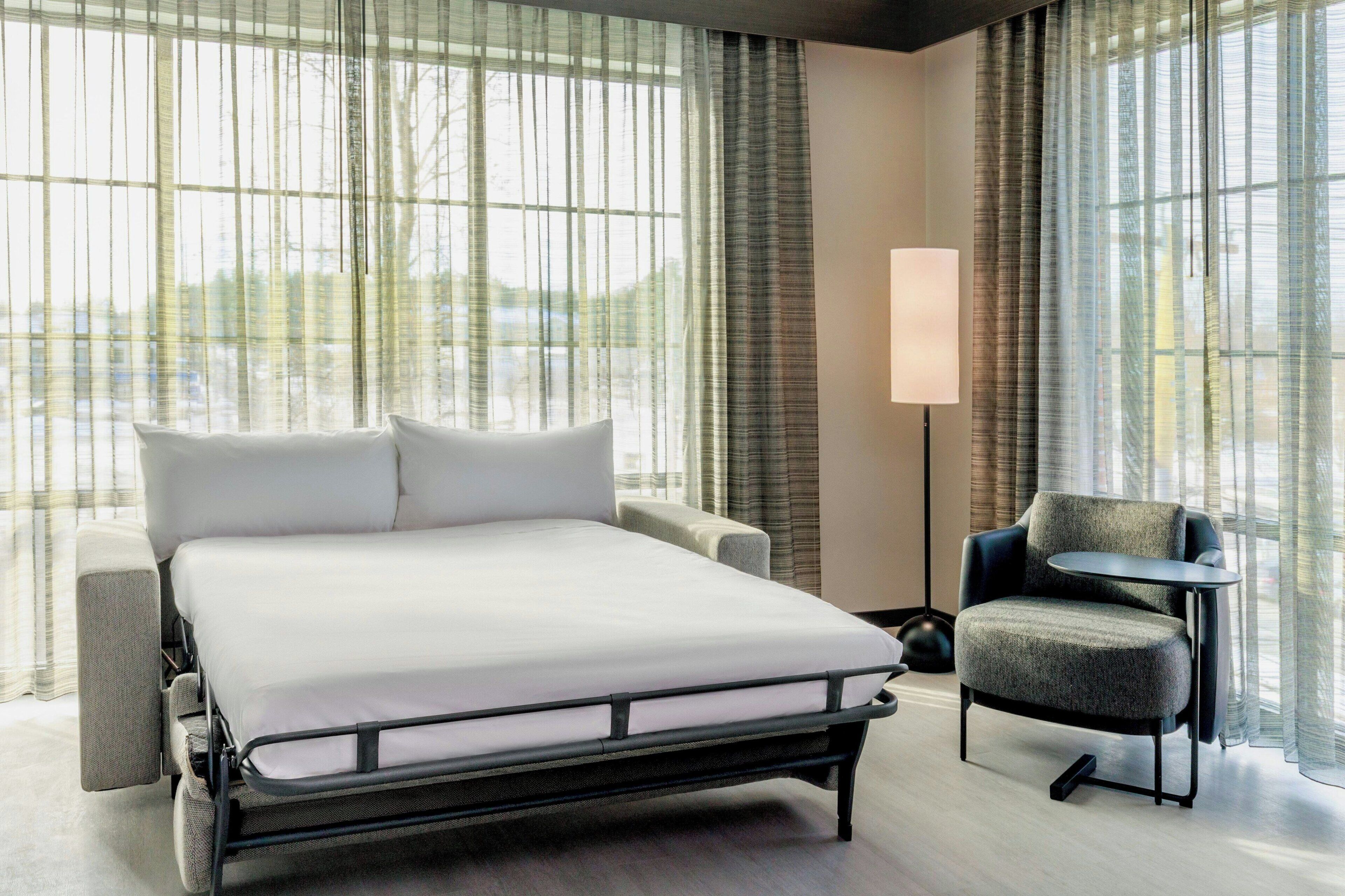 Een moderne hotelkamer met een groot bed, een klein rond tafeltje en een bank.