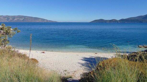 A beach with clear blue water, pebbly shore, and distant mountains. - Spacious villa with privacy and mountain views, near Agia Efimia & Myrtos beach (Makriotika, Kefalonia)